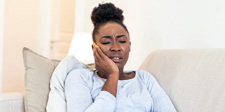 Woman with toothache sitting on couch at home