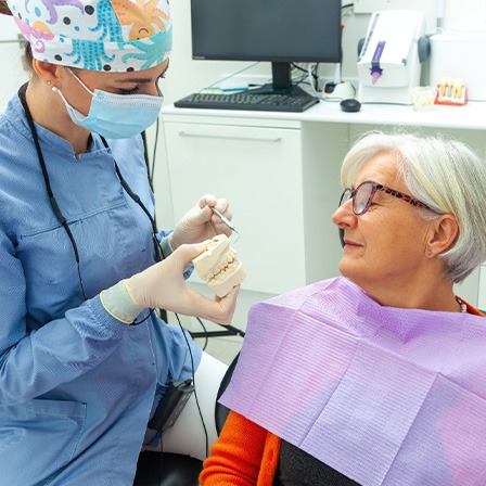 Older woman looking at new smile while learning about dental implant post-op instructions in Oklahoma City 