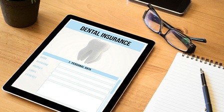Dental insurance form on tablet next to office supplies