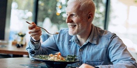 An older man eating healthy at a restaurant