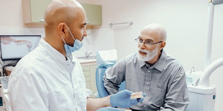 An older man talking to his dentist about dentures