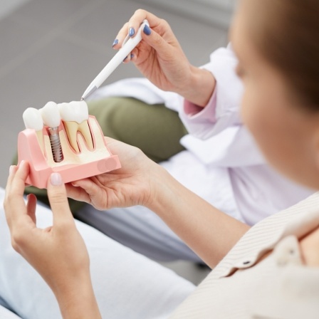 Dentist showing a patient a model of dental implants in Oklahoma City