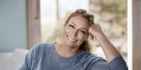 Woman in gray blouse smiling on couch