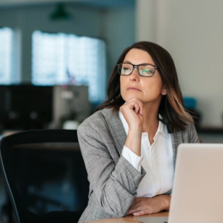 Woman looking pensive while sitting at desk with laptop