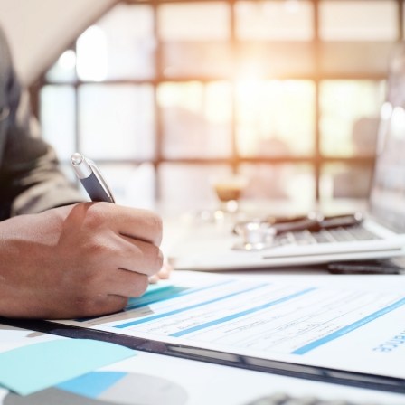 Person filling out paper form on clipboard