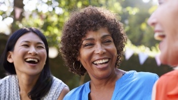 Three women laughing together outdoors