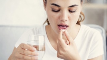Woman taking pill with glass of water