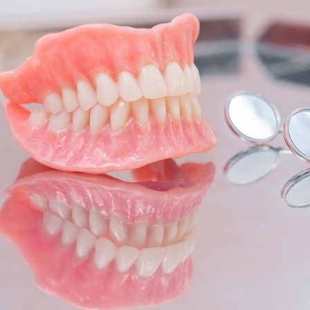 Dentures on tray next to two dental mirrors