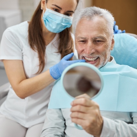 Senior dental patient admiring his smile in mirror