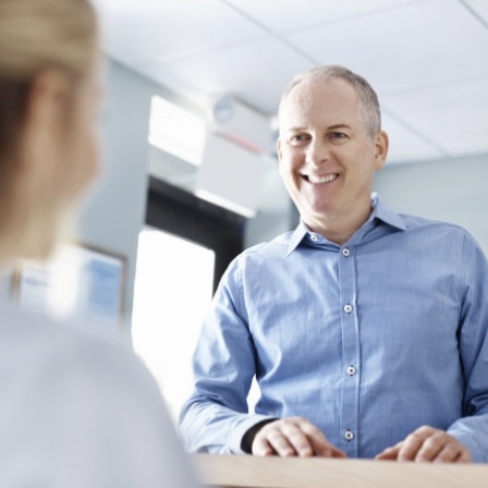 Man smiling at dental office receptionist