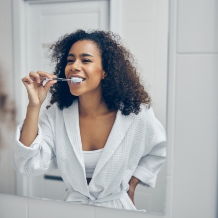 Woman smiling while brushing her teeth