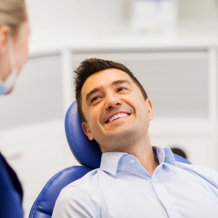 Man in dental chair smiling at his dentist