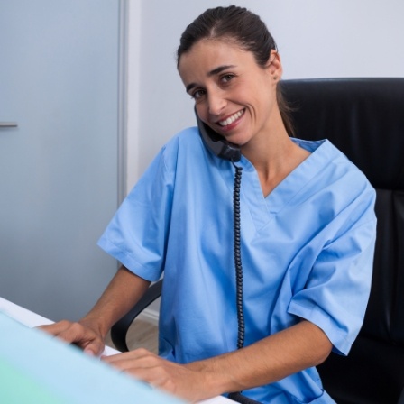 Dental team member talking on phone and sitting at computer