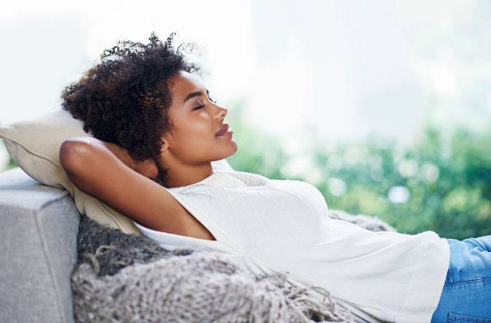 Woman laying down with her eyes closed and her hands behind her head