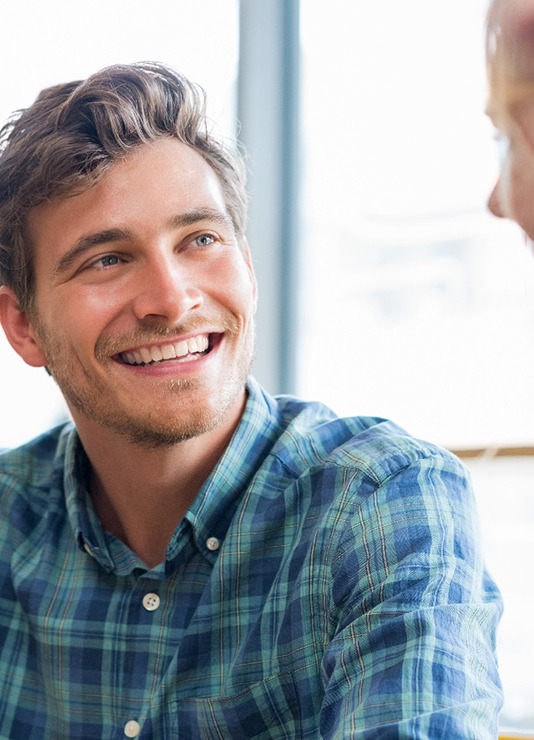 man smiling while talking to friend