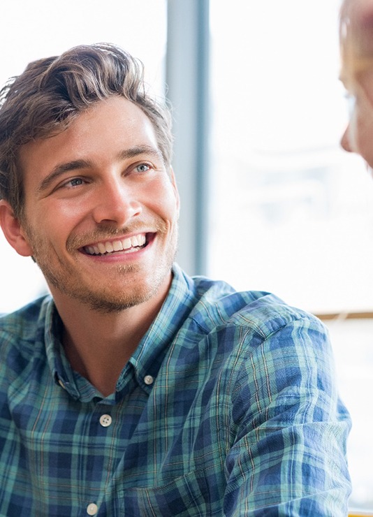 Man smiling while talking to friend