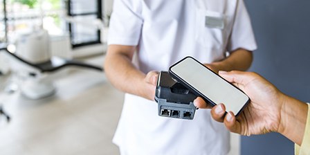 Staff in white scrubs scanning patient’s phone for virtual payment