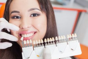 woman smiling beside porcelain veneer samples