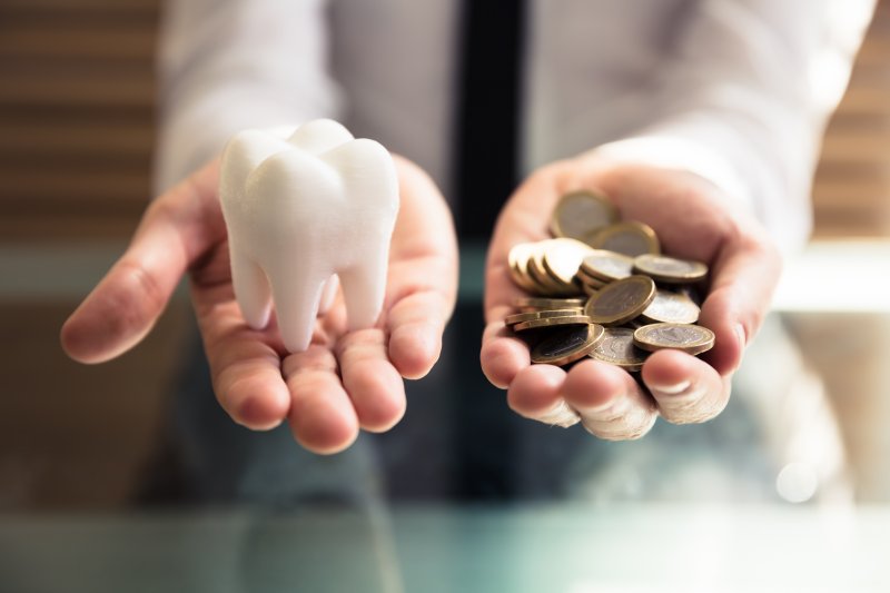 Person holding fake tooth in one hand and coins in the other