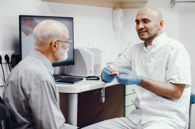 Dentist explaining how denture adhesive works