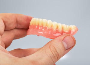 Close-up of denture held between finger and thumb
